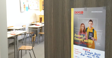 Zdjęcie przedstawia otwarte drzwi do sali lekcyjnej. Na drzwiach wisi plakat z informacją o akcji. Wewnątrz klasy widać ławki i krzesła.